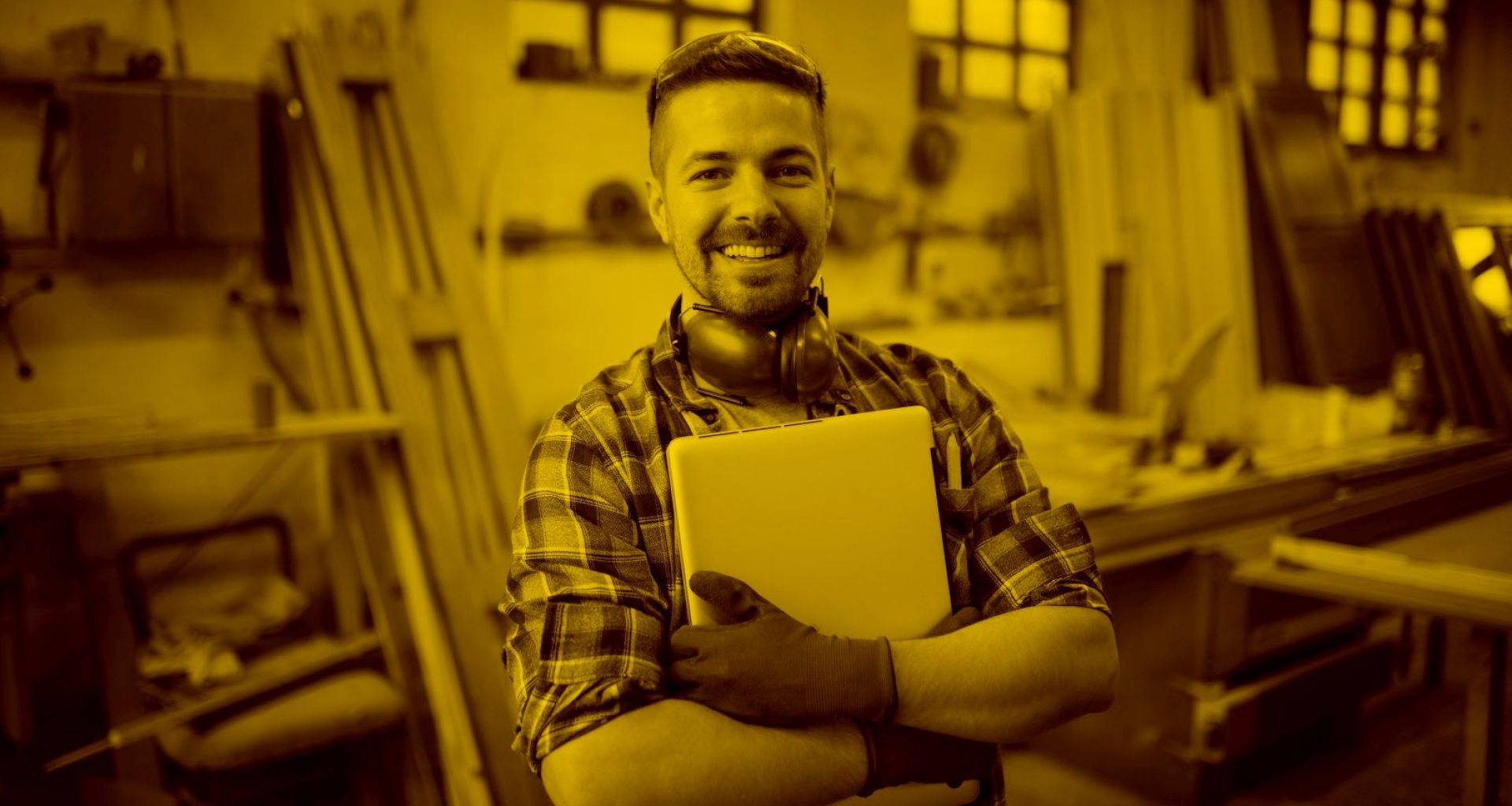 Handwerker mit Macbook in der Hand in der Werkstadt