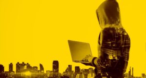 Verdeckter Hacker mit einem Laptop vor Gebäuden