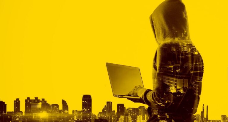 Verdeckter Hacker mit einem Laptop vor Gebäuden